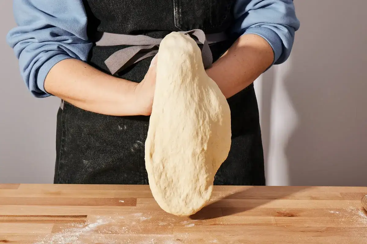 Ręce formują ciasto na idealną pizzę na cienkim cieście.