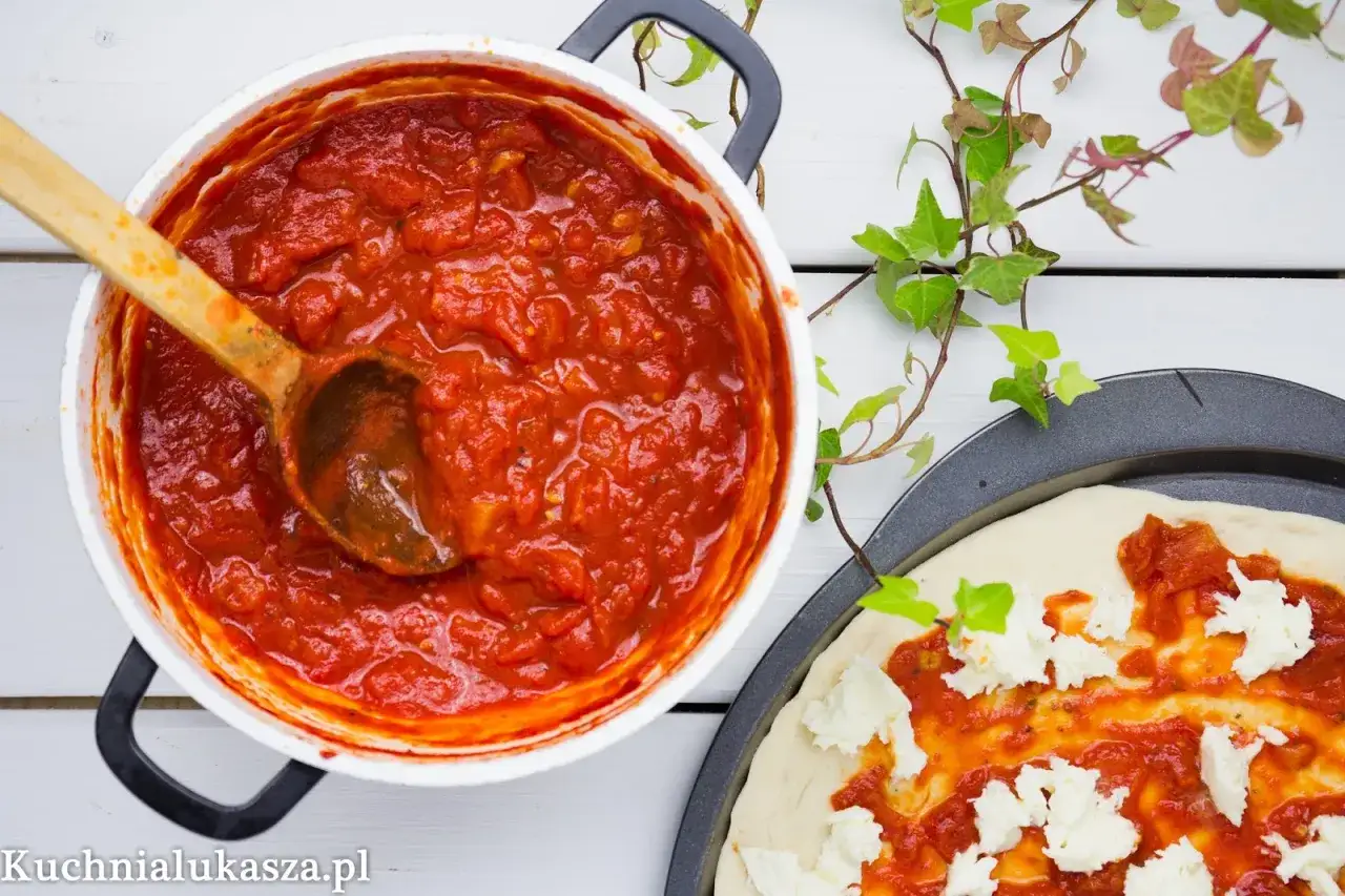 Gęsty, aromatyczny sos do pizzy w garnku, obok surowe ciasto z mozzarellą. Idealny na domową pizzę.