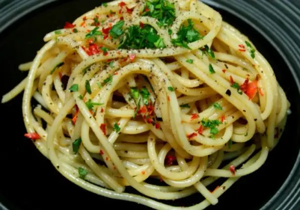Pyszne spaghetti aglio e olio peperoncino, posypane natką pietruszki i pieprzem.